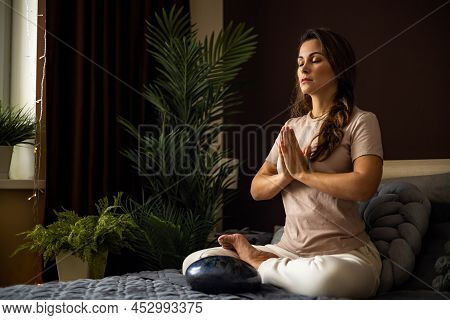 Relaxed Yoga Woman Meditation In Lotus Position With Hands Namaste On Bed At Bedroom