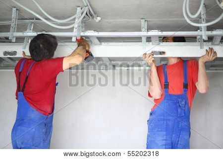 The two men set the ceiling profile in the apartment
