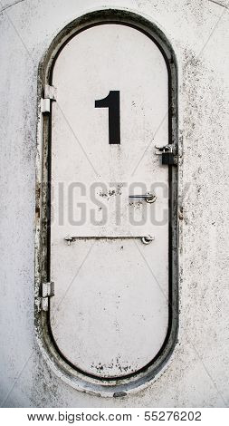 Dirty White Oval Metal Door With The Number 1 Written On It