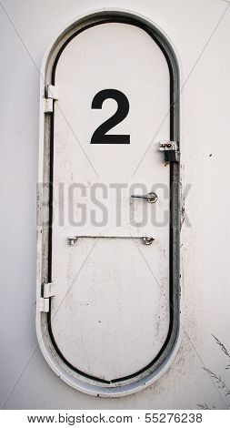 Dirty White Oval Metal Door With The Number 2 Written On It
