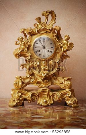 Antuque ornate golden clock on marble table, closeup.