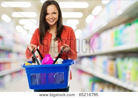 Beautiful cheerful brunette woman with basket full of cleansers in a shop