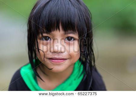 BANAUE, PHILIPPINES, DECEMBER 04 : A young unidentified Filipino little girl is posing under the rain in the village of Banaue, north Luzon, Philippines, on december 04, 2013