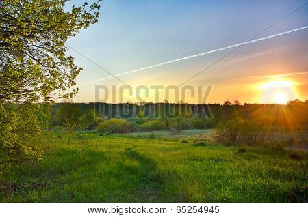 Landscape With The Sunrise Over The Meadow And Lines From The Aircraft In The Sky