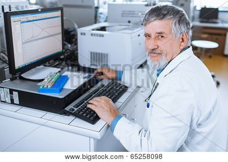 Senior researche rusing a computer in the lab while working on an experiment (color toned image)