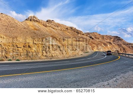 Highway along mountains of Arava desert under beautiful cloudy sky in Israel.