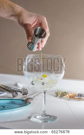 Barman pouring drink to prepare gin tonic cocktail