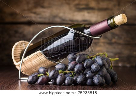 Red Wine With Cluster Of Dark Blue Grapes At Wooden Table.