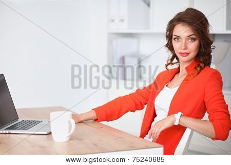 Attractive woman sitting at desk in office, working with laptop