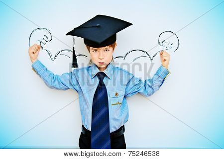 Smart boy stands by the whiteboard in a classroom expressing the power of knowledge. Educational concept. Copy space.