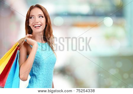 Shopping concept. Beautiful young woman with shopping bags on shop background