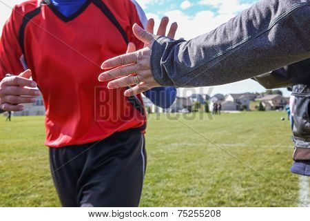 High Five line after a child's soccer game. Some motion blur, focus on arm