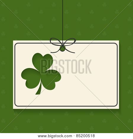 Blank hanging card with Irish lucky clover leaf on green background for Happy St. Patrick's Day celebration.