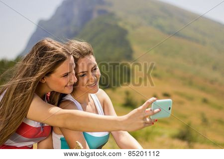 Girl on mountain with mobile phone taking self-ie
