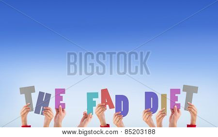 Hands holding up the fad diet against bright blue sky
