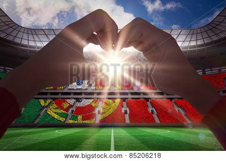 Woman making heart shape with hands against stadium full of portugal football fans