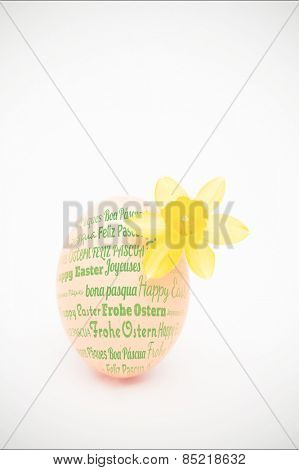 Happy easter in different languages against egg with a small daffodil