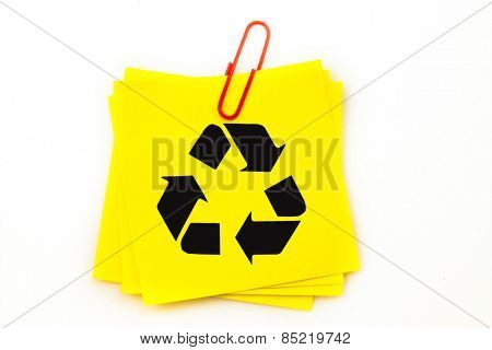 Recycling symbol against sticky note with red paperclip