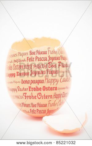 Happy easter in different languages against egg with top of shell broken off