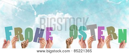 Hands holding up frohe ostern against blue sky