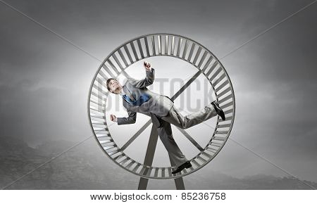 Young businessman running in huge hamster wheel