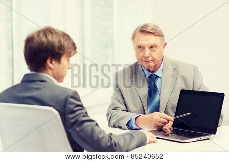 business, advertisement, technology and office concept - older man and young man with laptop computer in office