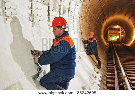 Tunneller worker installing fixture in underground subway metro construction site