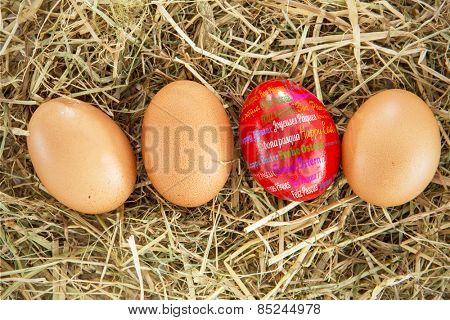 Happy easter in different languages against red egg on straw with plain ones