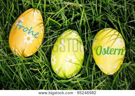frohe ostern against three easter eggs nestled in the grass