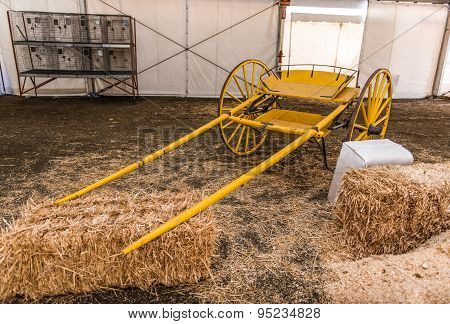 Yellow Empty Carriage Sits Near Hay Bales