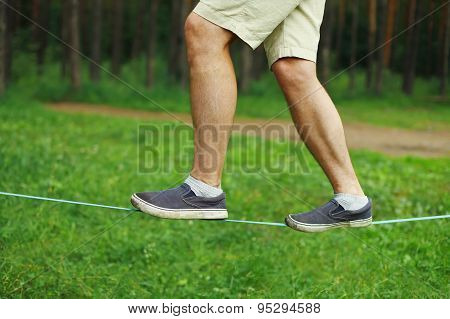 Sport, Leisure, Recreation And Healthy Lifestyle Concept - Man Slacklining Walking And Balancing On