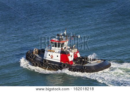Red and White Tug Boat on the open ocean from above.