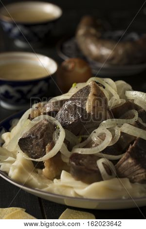 National Kazakh dish - Beshbarmak prepared with horse or lamb meat and pasta on the dark wooden table