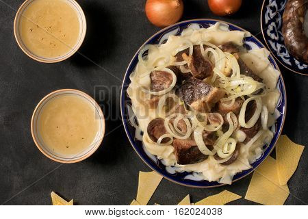 National Kazakh dish - Beshbarmak prepared with meat and pasta on the dark chalkboard