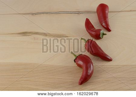 Raw uncooked whole red chili peppers on wood table