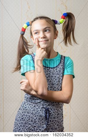 11 year old girl with pigtails like Pippi Longstocking is thoughtfully pressing a finger to her cheek. the concept of decision making.