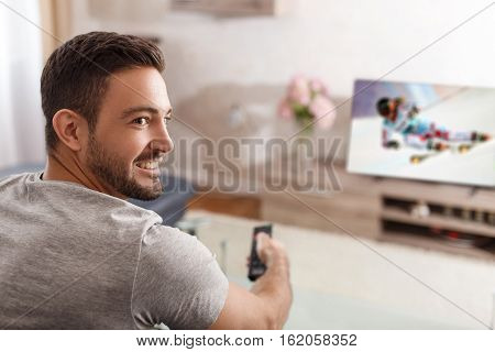 Excited man switch TV to ski rading by remote control