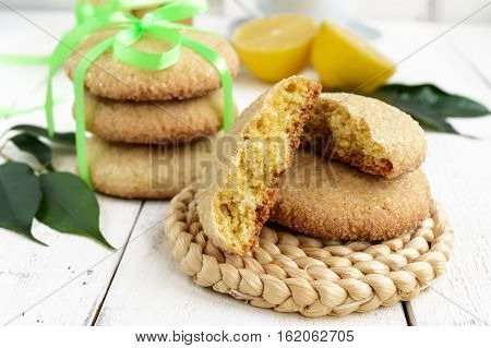 Shortbread lemon flavored cookies: a broken and connected green ribbon for a gift. Fresh lemon on a white wooden background. Close up