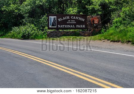GUNNISON COLORADO: June 28 2015. A wide view across the road from the sign welcoming visitors to the Black Canyon of the Gunnison National Park