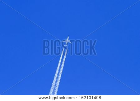 the plane flies on the surface of the blue sky leaving a white trail air
