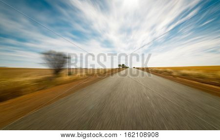 Straight road goes to horizon on background of ble sky and Golden wheat field.