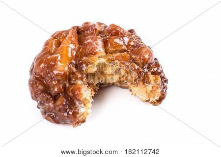 A Frosted Apple Fritter Donut With A Bite Out Of It Isolated On A White Background