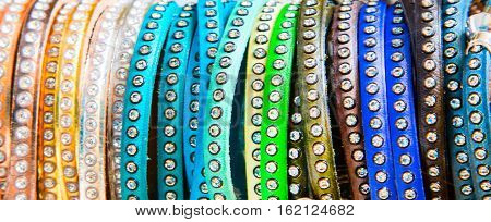 The row of many multicolored bracelets close up banner fashion background