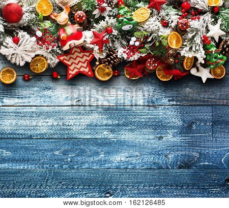 Merry Christmas Frame with green pine, colorful baubles, knots with berries,stars, orangesand other seasonal stuff over an old wooden aged background
