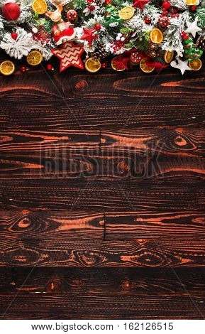 Merry Christmas Frame with green pine, colorful baubles, knots with berries,stars, orangesand other seasonal stuff over an old wooden aged background