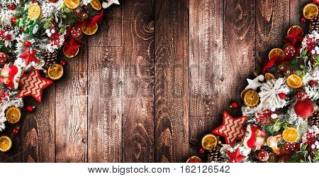 Merry Christmas Frame with green pine, colorful baubles, knots with berries,stars, orangesand other seasonal stuff over an old wooden aged background