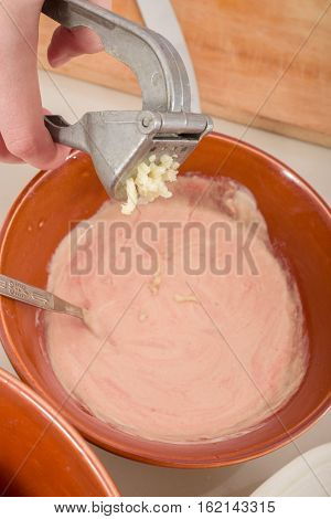 female hands pressing garlick to a sauce