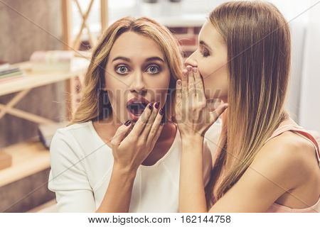 Beautiful girl is whispering to her friend during a party