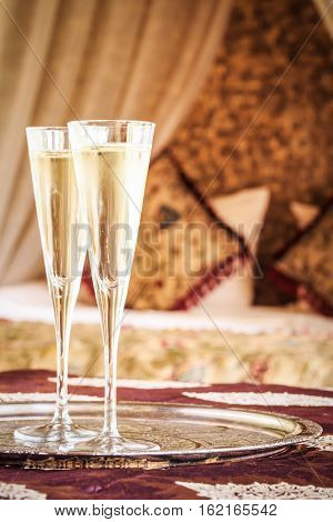 Two Champagne Glasses With Oriental Canopy Bed At The Background