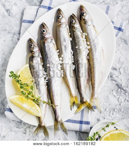 The freshest fish of the northern sea ice fishing smelt with the scent of fresh cucumber on a light background marble with lemon and herbs. Top view